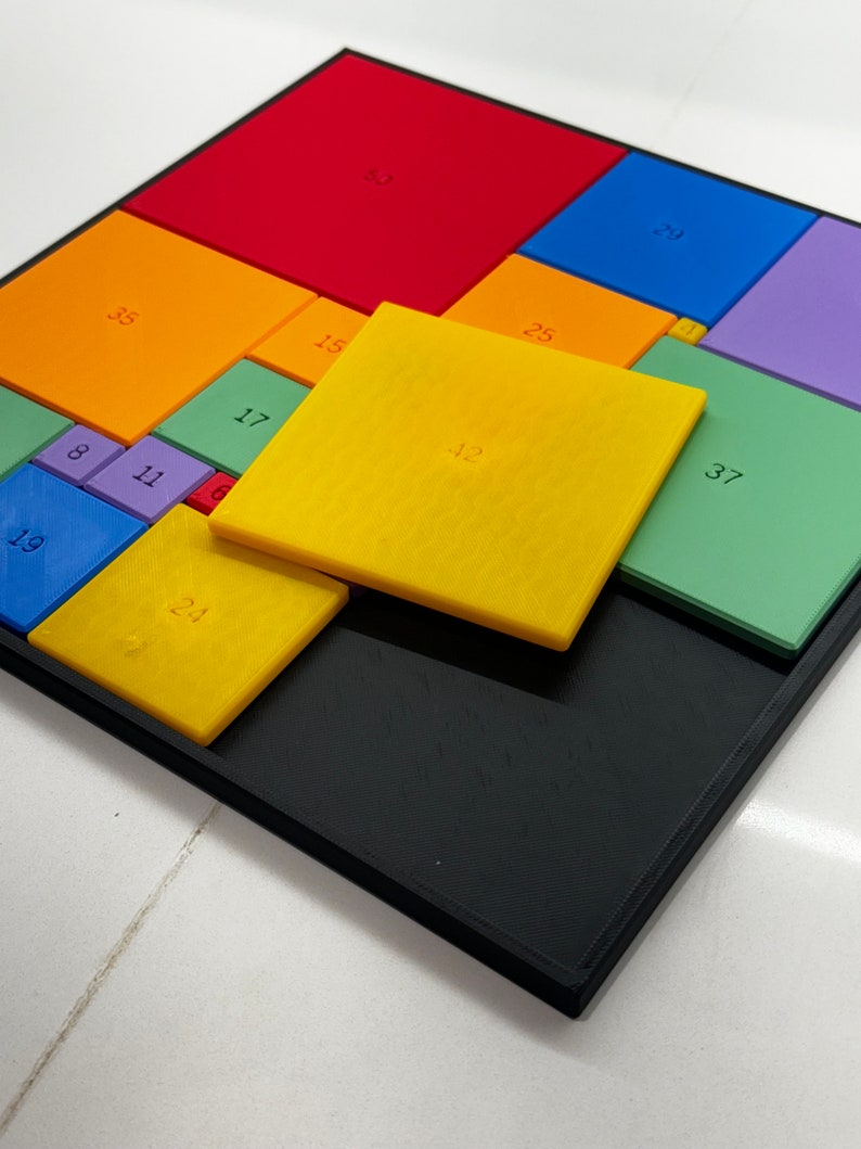 May include: A colorful puzzle with different sized squares, each with a number printed on it. The numbers include 8, 11, 17, 19, 23, 25, 29, 35, 37, 50, and 12. The puzzle is made of plastic and is set on a black frame.