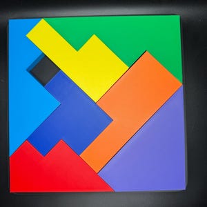 May include: A colorful wooden puzzle with seven pieces in different shapes and colors, including blue, yellow, green, orange, red, and purple. The pieces fit together to form a square.