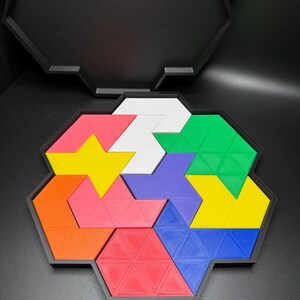 May include: A colorful geometric puzzle with 10 pieces in a black hexagonal frame. The pieces are in shades of red, orange, yellow, green, blue, purple, and white.