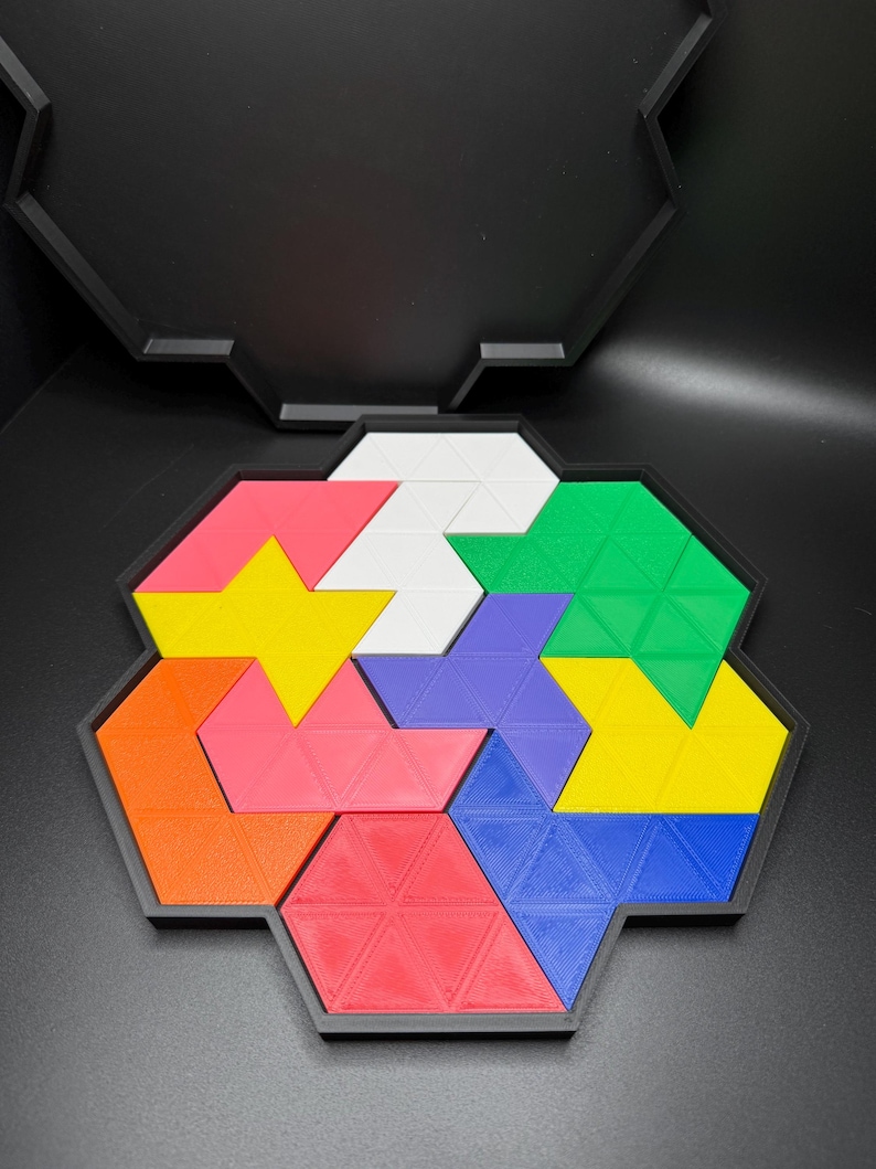 May include: A colorful geometric puzzle with 10 pieces in a black hexagonal frame. The pieces are in shades of red, orange, yellow, green, blue, purple, and white.