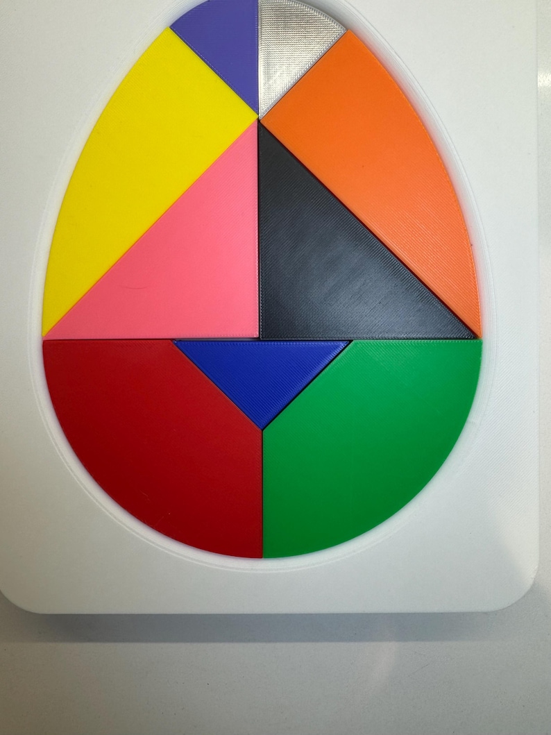 Op de afbeelding: Een ronde puzzel met acht stukken in verschillende kleuren: geel, roze, rood, groen, blauw, zwart, oranje en paars. De stukken passen in elkaar om een cirkel te vormen.