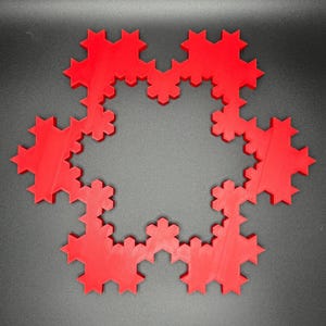 May include: A red, 3D printed snowflake design with a circular shape and a detailed, intricate pattern.