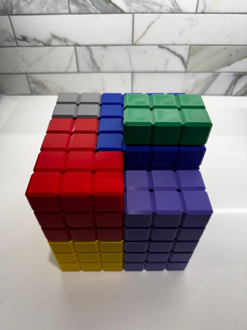 May include: A colorful cube made of small blocks. The cube is made of red, yellow, blue, green, and gray blocks. The blocks are arranged in a pattern.