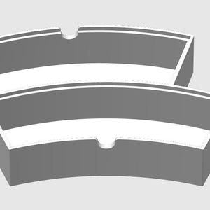 May include: A gray ashtray with a curved design. The ashtray has a white stripe and a small indentation for resting cigarettes. The design is modern and minimalist.