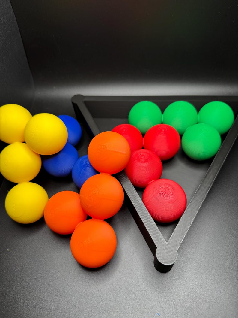 Peut inclure: Un ensemble de boules color&eacute;es dans un plateau triangulaire. Les boules sont rouges, vertes, bleues et jaunes. Le plateau est noir et a une forme triangulaire.