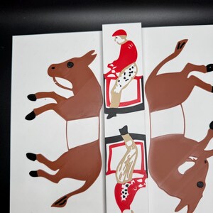 May include: Two brown donkey figures with a red and white jockey riding each one. The figures are cut out and ready to be assembled.