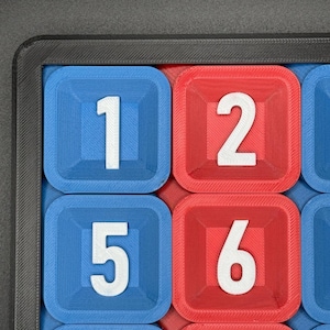 Pu&ograve; includere: Primo piano di una scacchiera con caselle blu e rosse. Ogni casella ha un numero bianco. I numeri sono 1, 2, 5, 6, 9 e 10.