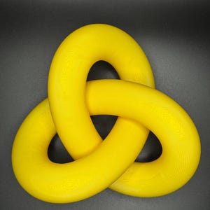 May include: A bright yellow, three-dimensional knot sculpture. The knot is made of three intertwined loops, each with a circular shape.