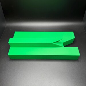 May include: A bright green plastic object with a unique shape, resembling a ramp or a bridge. It is made of two pieces that fit together.