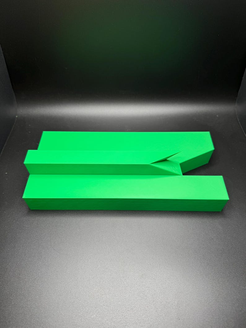 May include: A bright green plastic object with a unique shape, resembling a ramp or a bridge. It is made of two pieces that fit together.