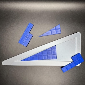 May include: A blue triangle puzzle with four pieces. The pieces are made of a grid of small squares. The puzzle is on a gray background.