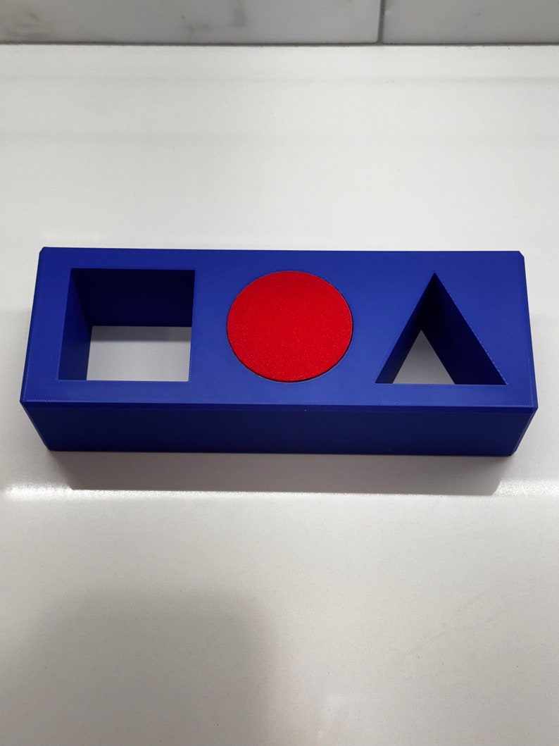 May include: A blue rectangular block with three cutouts: a square, a circle, and a triangle. The circle cutout is filled with a red circle.