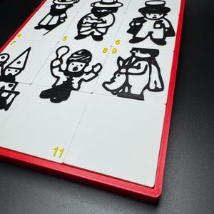 May include: A white board with a red frame and eleven numbered squares. Each square contains a black and white illustration of a person. The numbers 1, 2, 3, 4, 5, 6, 9, and 11 are visible.