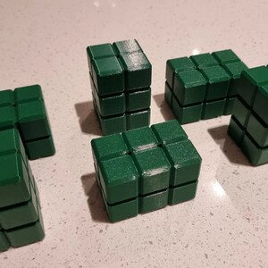 May include: Six green building blocks made of plastic. Each block is made up of smaller cubes, creating a textured surface.