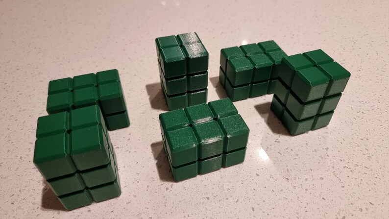 May include: Six green building blocks made of plastic. Each block is made up of smaller cubes, creating a textured surface.