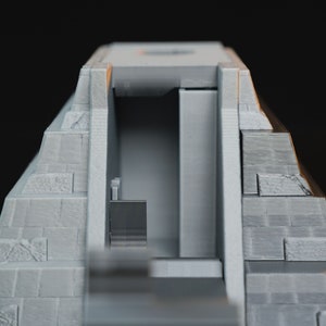 May include: A gray 3D printed model of a pyramid with a doorway and an interior. The pyramid is made of stacked blocks.