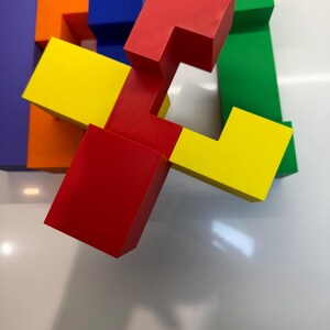 May include: A colorful set of interlocking puzzle blocks made of plastic. The blocks are red, yellow, green, blue, and orange. The blocks are arranged in a way that creates a three-dimensional shape.