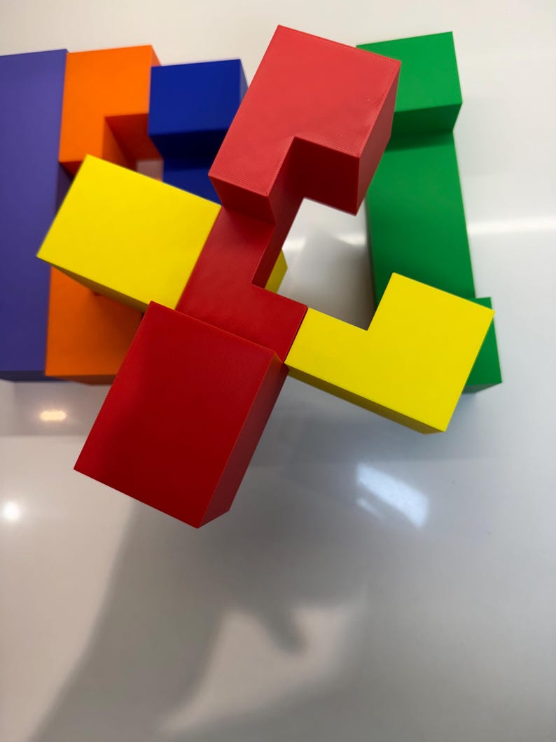 May include: A colorful set of interlocking puzzle blocks made of plastic. The blocks are red, yellow, green, blue, and orange. The blocks are arranged in a way that creates a three-dimensional shape.