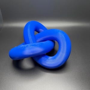 May include: A blue, three-dimensional knot sculpture made of plastic. The knot is a simple, continuous loop that is tied in a way that creates a complex and interesting shape.