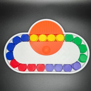 May include: A white cloud-shaped sensory toy with a red, blue, green, and yellow circle pattern. The toy has a central orange section with a series of yellow circles.