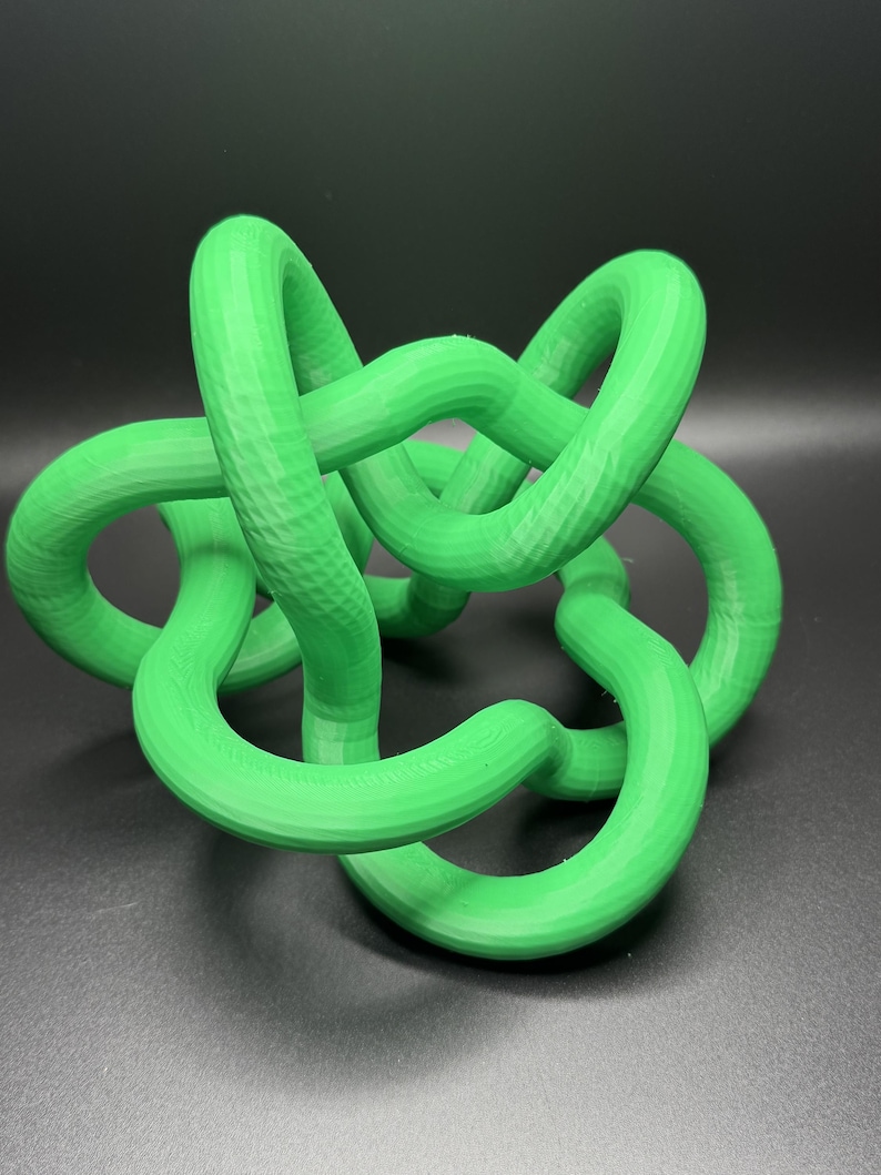 K&ouml;nnte beinhalten: Eine leuchtend gr&uuml;ne 3D-gedruckte Skulptur eines Knotens. Der Knoten besteht aus einem einzigen durchgehenden St&uuml;ck Plastik und ist als Dekorationsobjekt konzipiert.