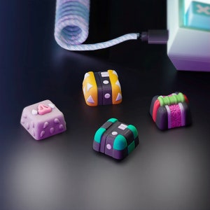 May include: Four colorful keycaps with different designs. The keycaps are made of plastic and have a variety of colors and patterns. The keycaps are designed for mechanical keyboards.
