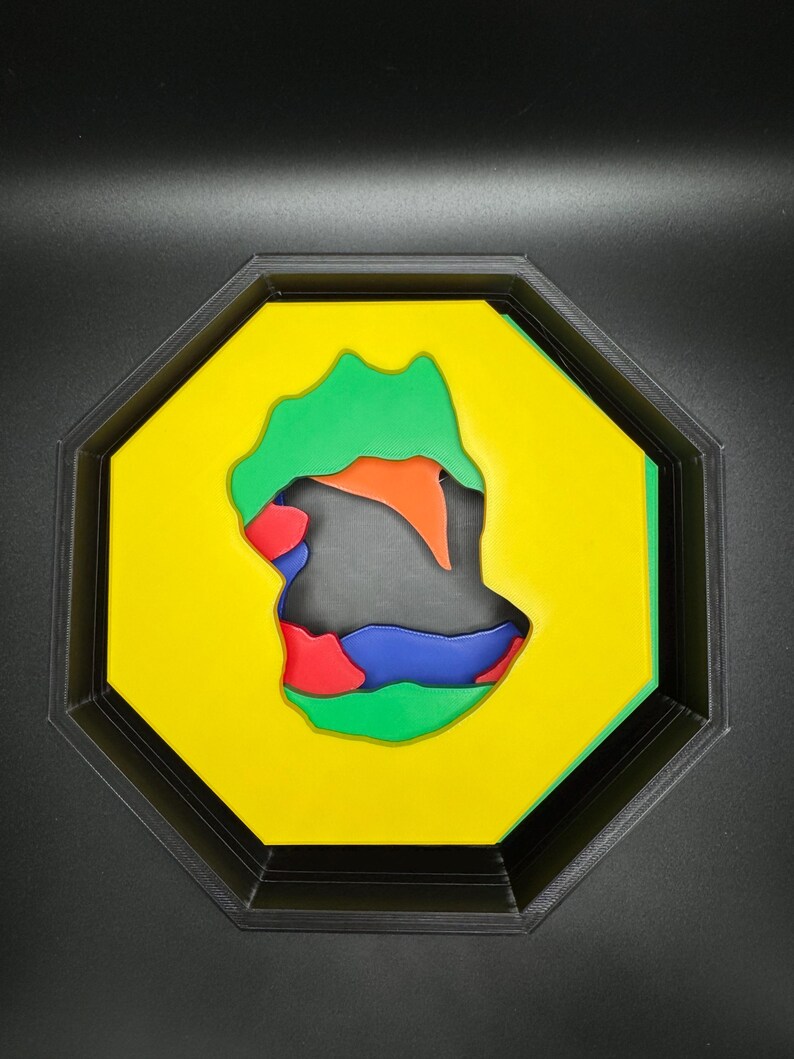 Op de afbeelding: Een geel achtkantig frame met een veelkleurig abstract ontwerp erin. Het ontwerp is gemaakt van groene, oranje, rode, blauwe en zwarte vormen.