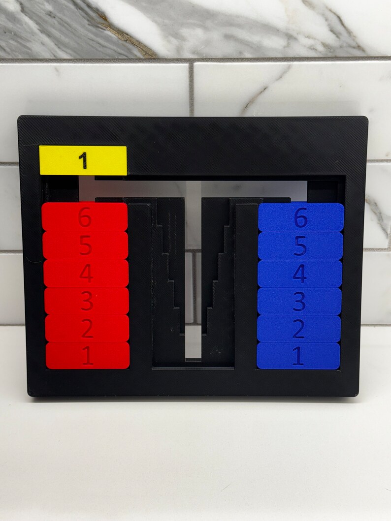 May include: A black frame with a yellow label that says "1" and two sets of red and blue number tiles. The red tiles are numbered 1 through 6 and the blue tiles are numbered 1 through 6.