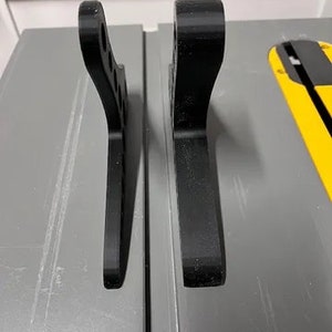 Może przedstawiać: Dwa czarne plastikowe elementy, obok siebie, o nieco innym wzorze. Elementy prawdopodobnie są do projektu druku 3D.