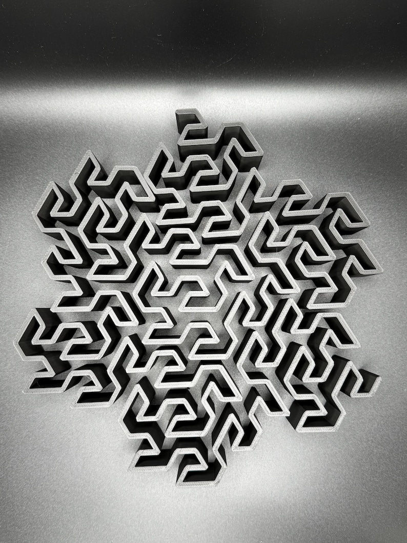 May include: A 3D printed black snowflake design with a complex maze pattern.