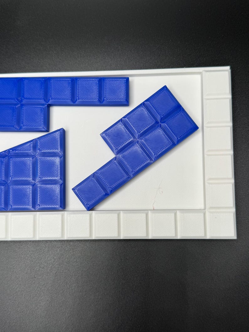 May include: Blue plastic puzzle pieces on a white puzzle board. The pieces are shaped like rectangles and squares.