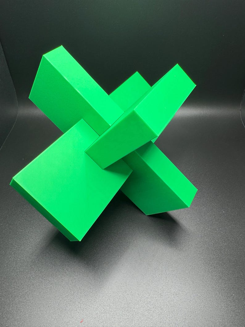 K&ouml;nnte beinhalten: Eine leuchtend gr&uuml;ne geometrische Skulptur aus vier sich schneidenden rechteckigen Prismen. Die Skulptur besteht aus einem glatten, kunststoffartigen Material.