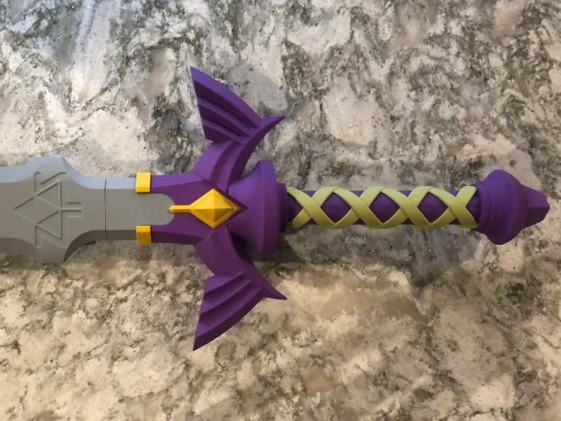 May include: A purple and gold sword with a detailed handle and a triangular design on the blade.
