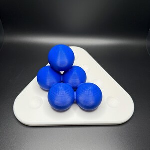 May include: A white triangular tray with six blue spheres arranged in a pyramid shape.