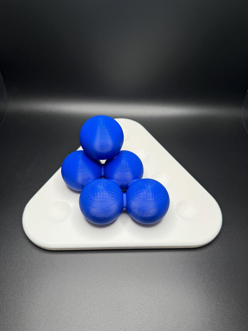 May include: A white triangular tray with six blue spheres arranged in a pyramid shape.