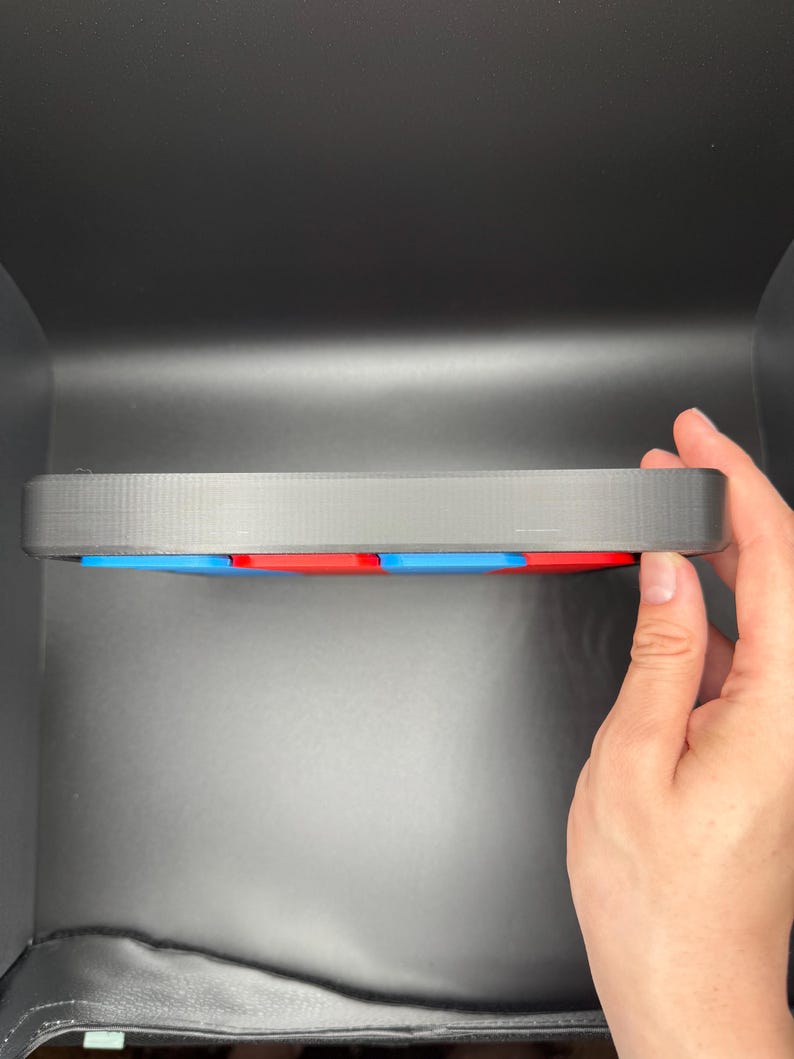 Pu&ograve; includere: Un vassoio di plastica nero con un bordo rialzato, che contiene un set di piastrelle quadrate colorate. Le piastrelle sono disposte in uno schema di blu, rosso e blu.