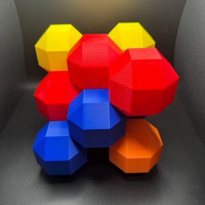 May include: A geometric sculpture made of 8 connected, multi-faceted shapes. The shapes are in red, yellow, blue, and orange.
