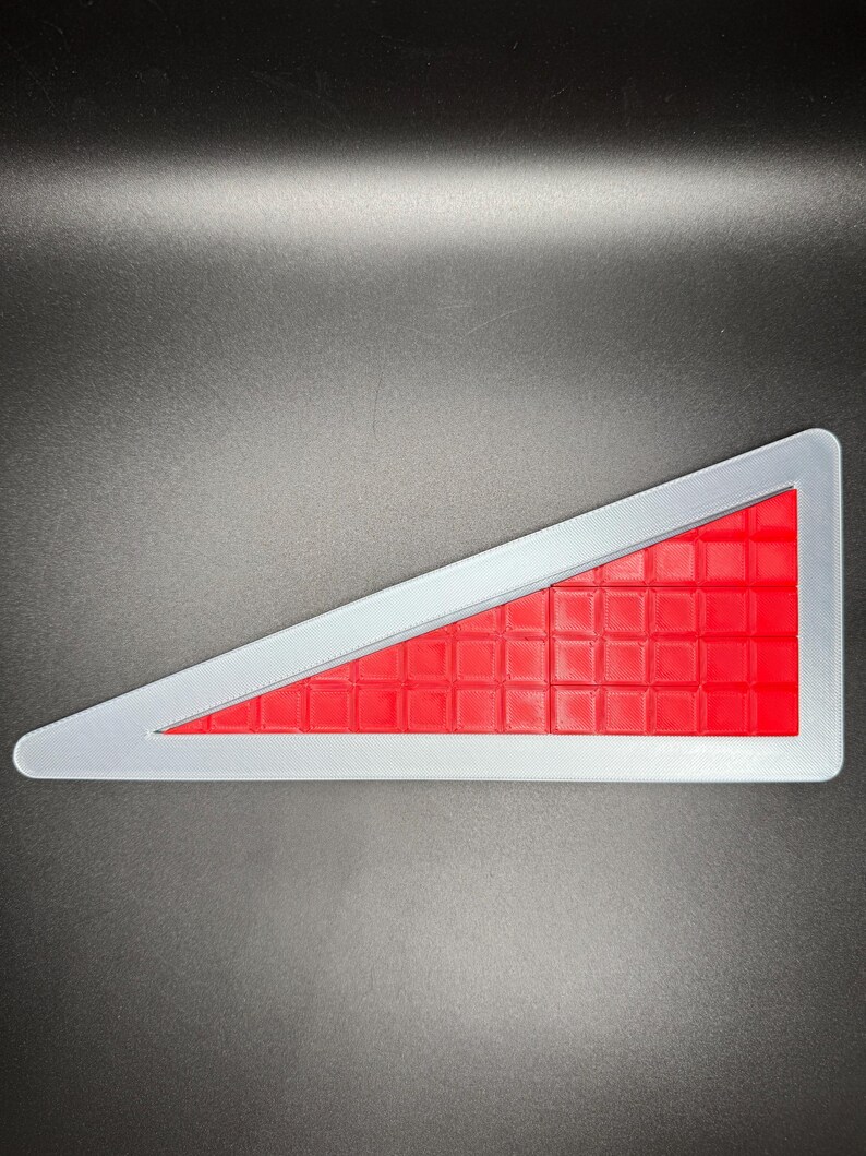 Puede incluir: Una se&ntilde;al de seguridad triangular roja y plateada con un patr&oacute;n de cuadr&iacute;cula.