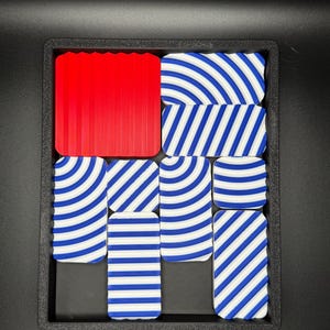 May include: A set of nine tiles with blue and white striped patterns. One tile is solid red.