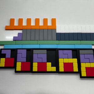 May include: Five black frames with different colored puzzle pieces inside. The pieces are arranged in a grid pattern and are made of plastic. The colors of the pieces are purple, red, yellow, and gray. The frames are all the same size and are made of black plastic.