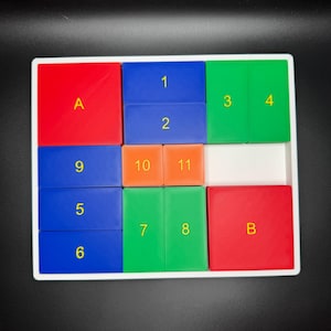 May include: A white tray with a grid of colorful tiles. The tiles are labeled with letters and numbers. The tiles are red, blue, green, and orange.