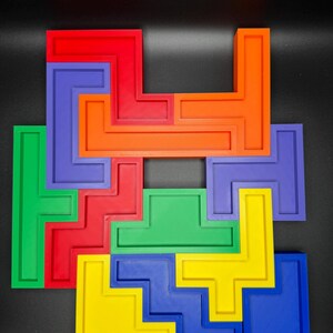 May include: A colorful puzzle made of interlocking plastic pieces. The pieces are shaped like L's and T's and are arranged in a pattern. The colors of the pieces are red, orange, yellow, green, blue, and purple.