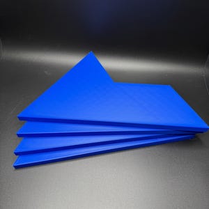 Peut inclure: Quatre pièces de puzzle bleues empilées les unes sur les autres. Les pièces sont en plastique texturé.