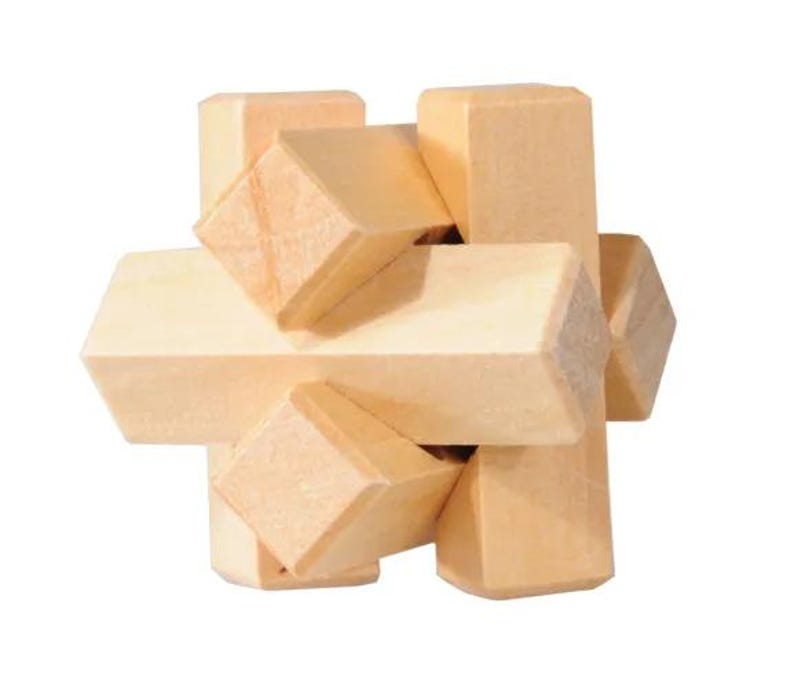 May include: A wooden puzzle with a complex design. The puzzle is made of multiple pieces that fit together to form a cube. The puzzle is made of light brown wood.