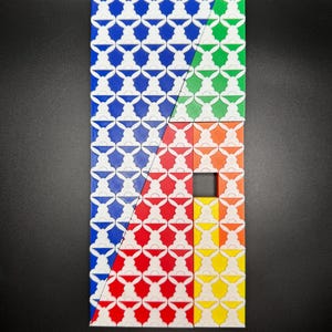 May include: A geometric pattern made of colorful tiles. The tiles are arranged in a diagonal pattern, with the colors blue, green, orange, red, and yellow. The tiles have a white pattern of stylized bunnies on them.