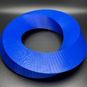 May include: A blue 3D printed Mobius strip, a continuous loop with a single twist, creating a unique geometric shape.