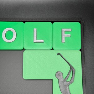 May include: Green and white tile letters spelling "GOLF" with a green background and a black silhouette of a golfer swinging a club.