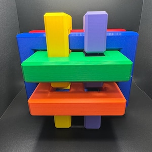 May include: A colorful interlocking puzzle made of five pieces. The puzzle is made of blue, green, red, orange, and purple plastic.