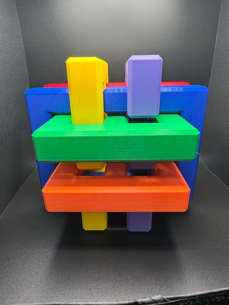 May include: A colorful interlocking puzzle made of five pieces. The puzzle is made of blue, green, red, orange, and purple plastic.
