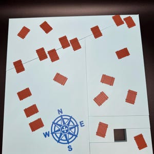 May include: A white board game with a blue compass rose and scattered red wooden bridge pieces. A thin gray line runs across the board. The game board is divided into sections.